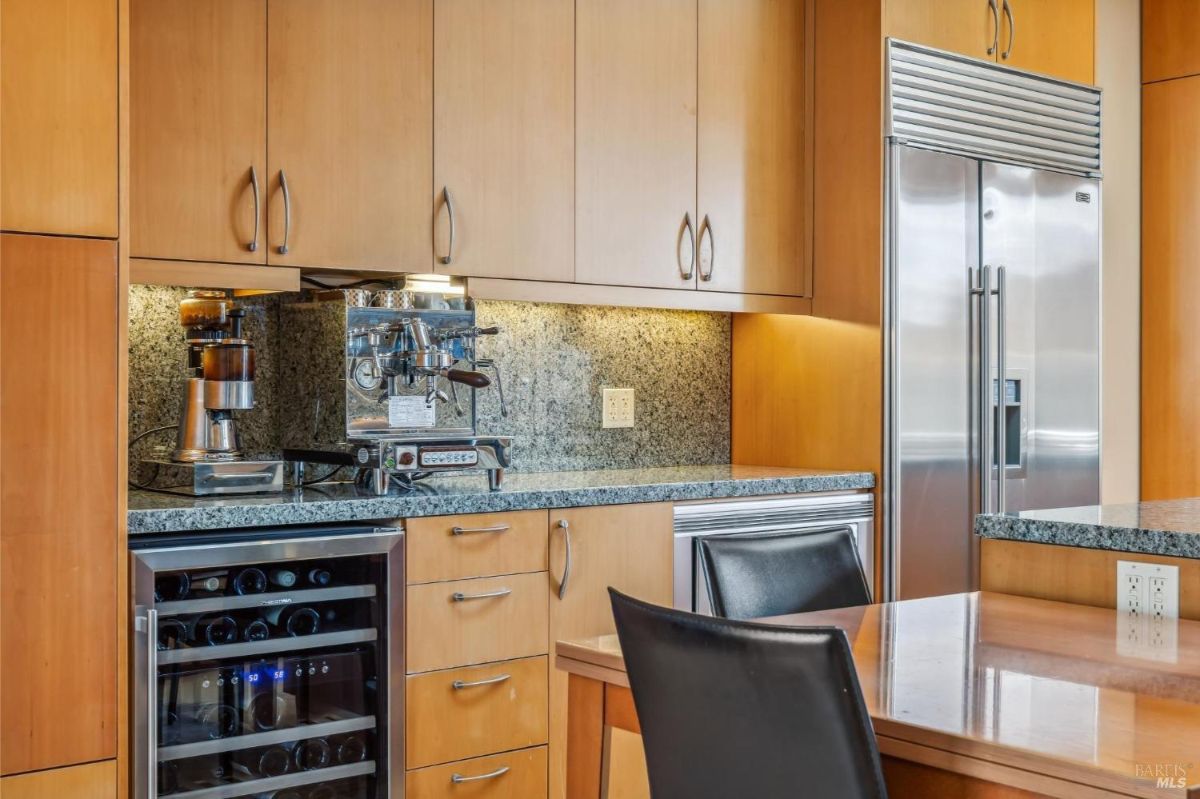 Kitchen with built-in coffee machine, wine cooler, and stainless steel refrigerator.