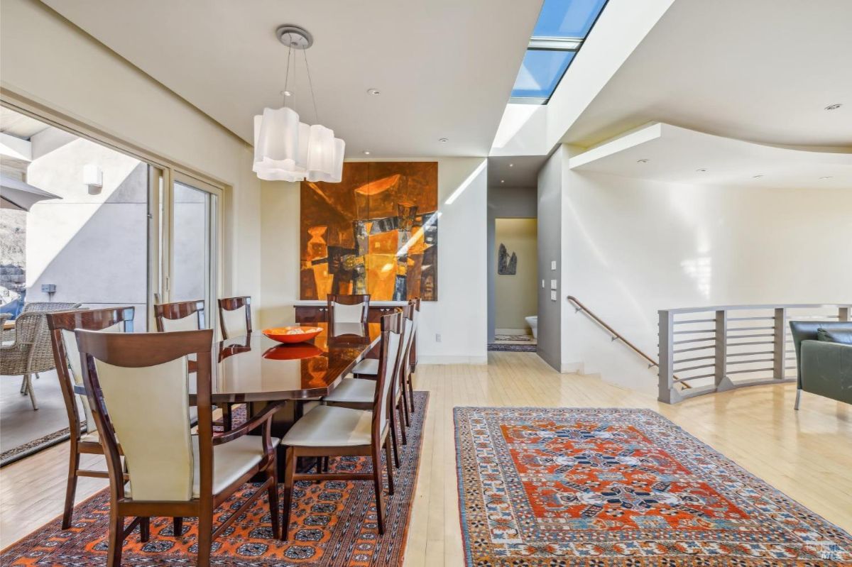 Dining area with a table, skylight, and sliding doors to an outdoor patio.