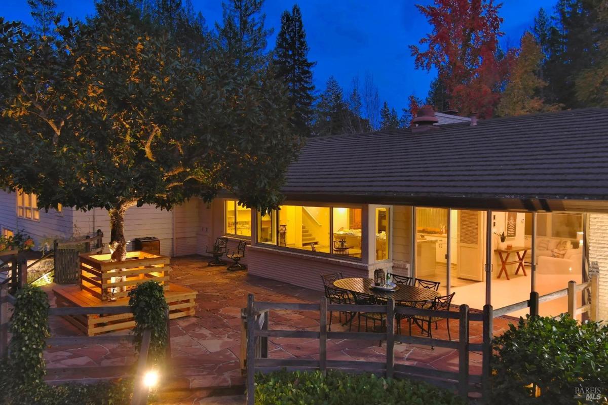House exterior with outdoor seating under a large tree at dusk.