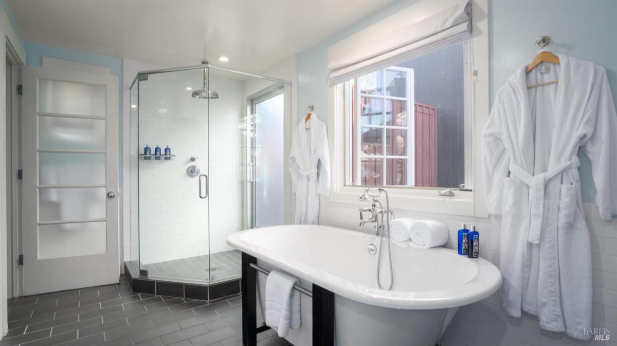 Bathroom with a freestanding tub, glass shower, and a window.