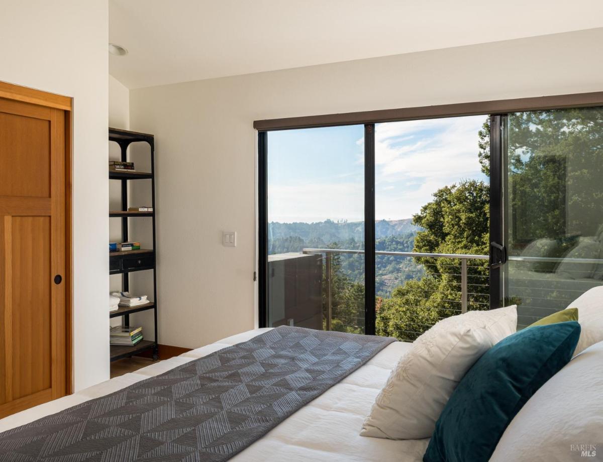 Bedroom with sliding doors opening to a view of trees and hills.