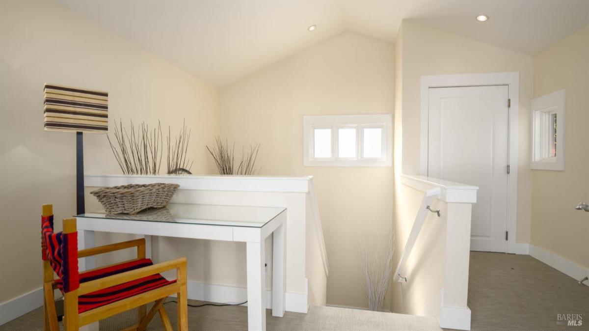 Upstairs landing area with a desk and chair near a staircase.