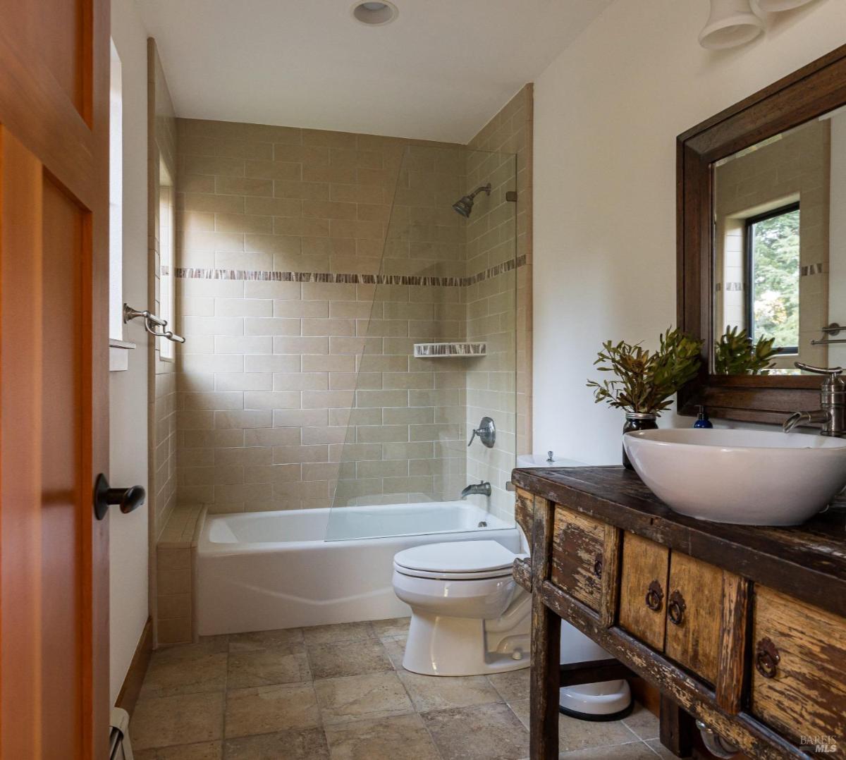 Bathroom with a tiled bathtub, sink, and wooden vanity.