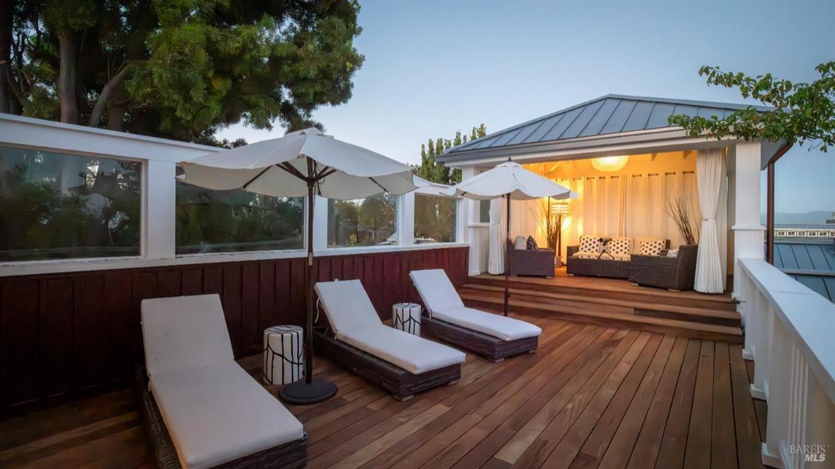 Rooftop deck with lounge chairs and a covered seating area.
