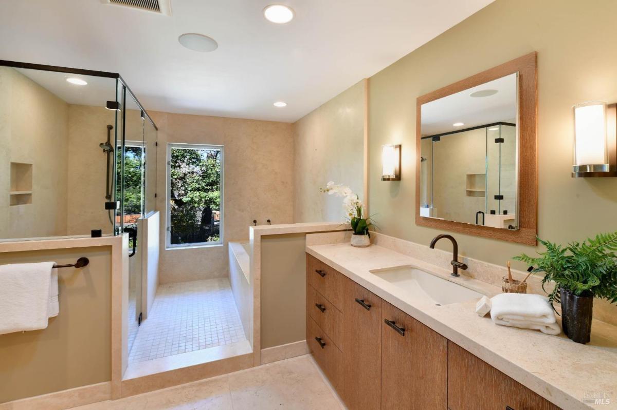 A bathroom with a walk-in shower, a bathtub, and a large window.