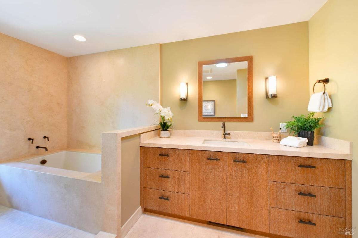 A bathroom with a soaking tub, a vanity, and neutral finishes.