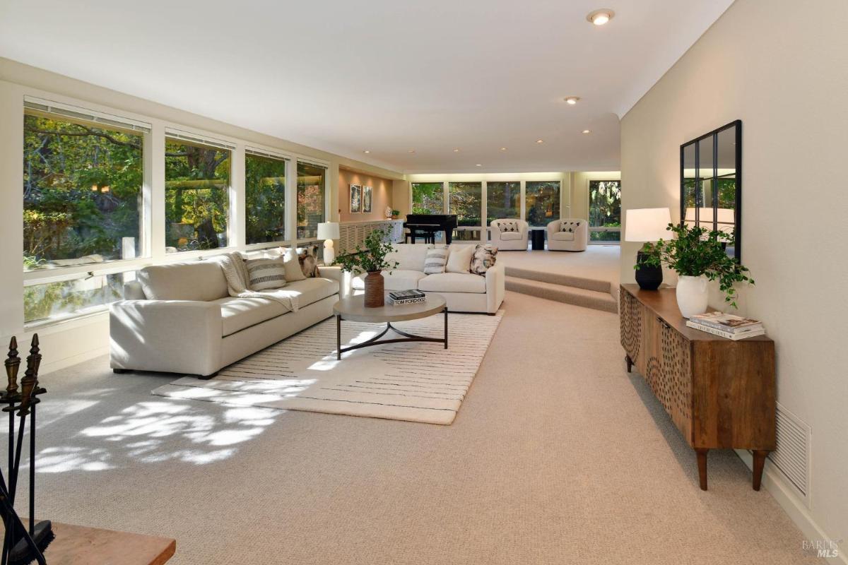 A spacious living room with large windows and multiple seating areas.