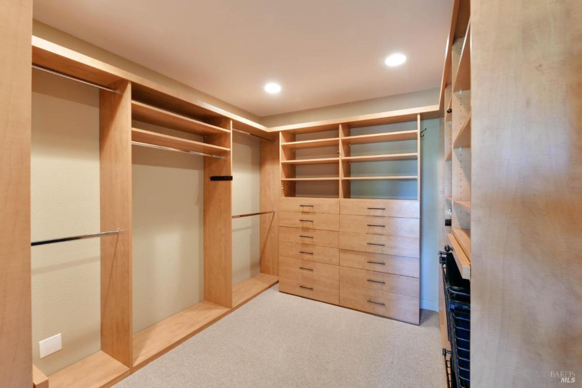 Walk-in closet with built-in shelves and drawers.