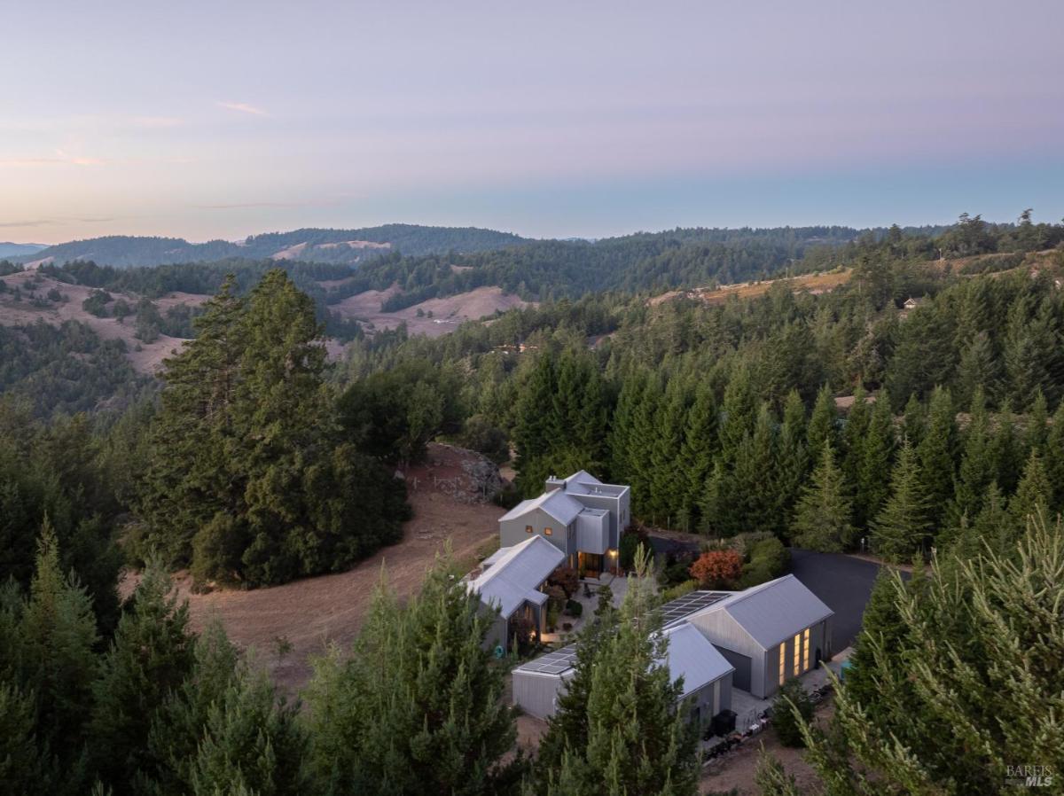 Distant view of a modern home in a forested valley.