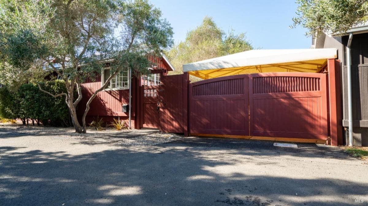 Red wooden gate and entrance with surrounding trees.
