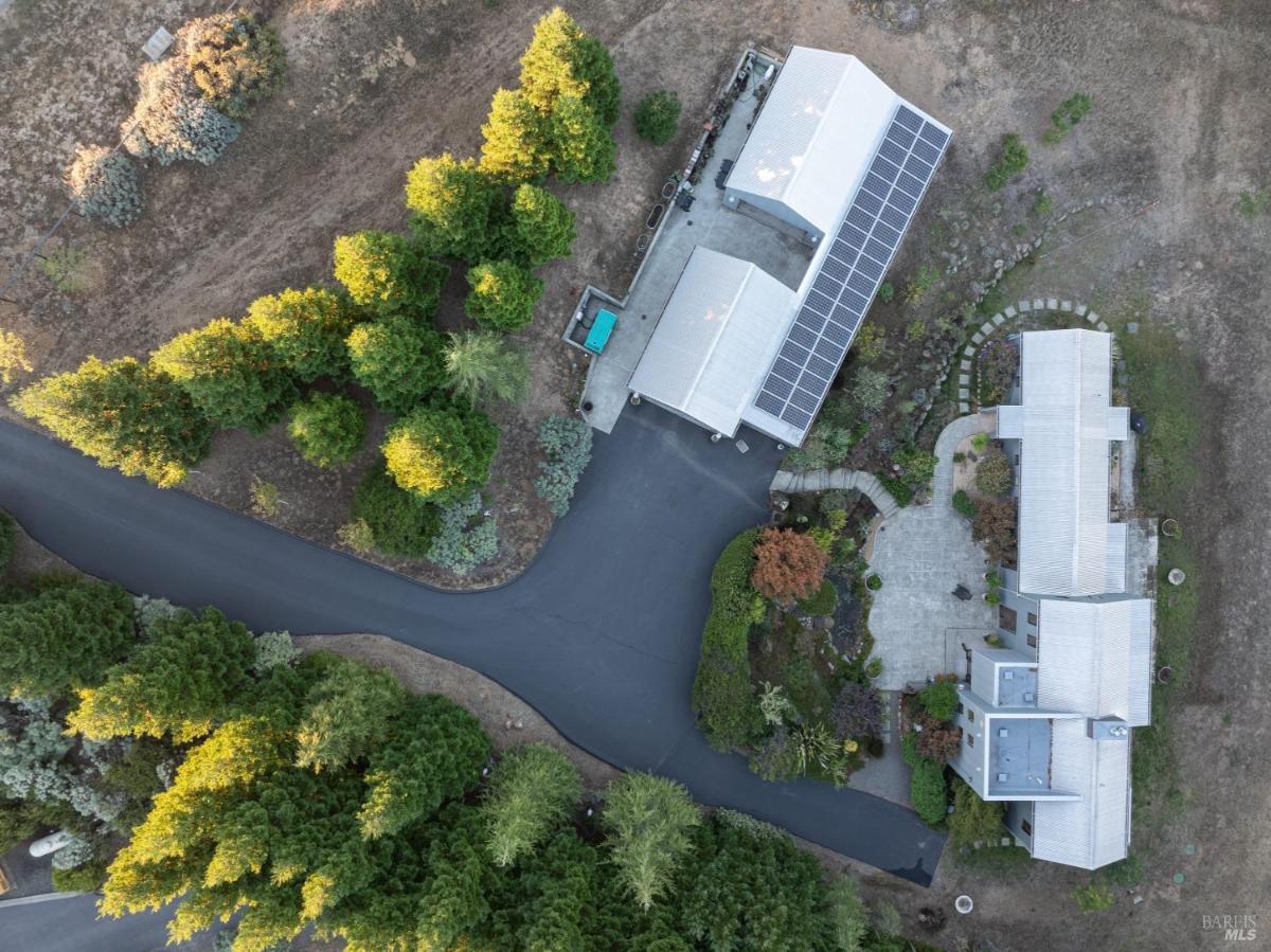 Overhead view of a property with a home, solar panels, and surrounding trees.