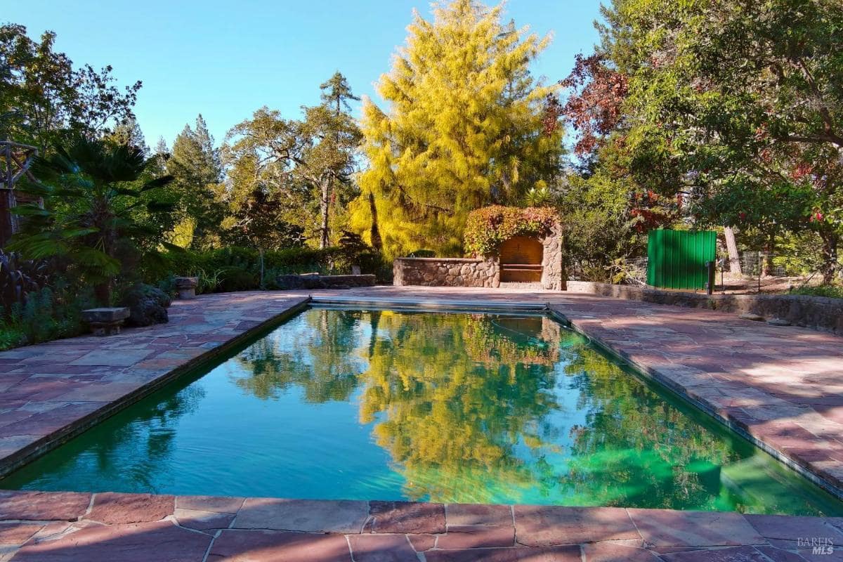 Outdoor pool surrounded by stone patio and landscaping.