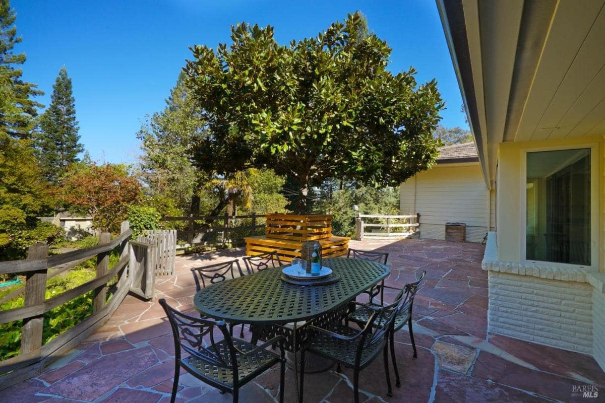 Outdoor dining area on a stone patio under a large tree.