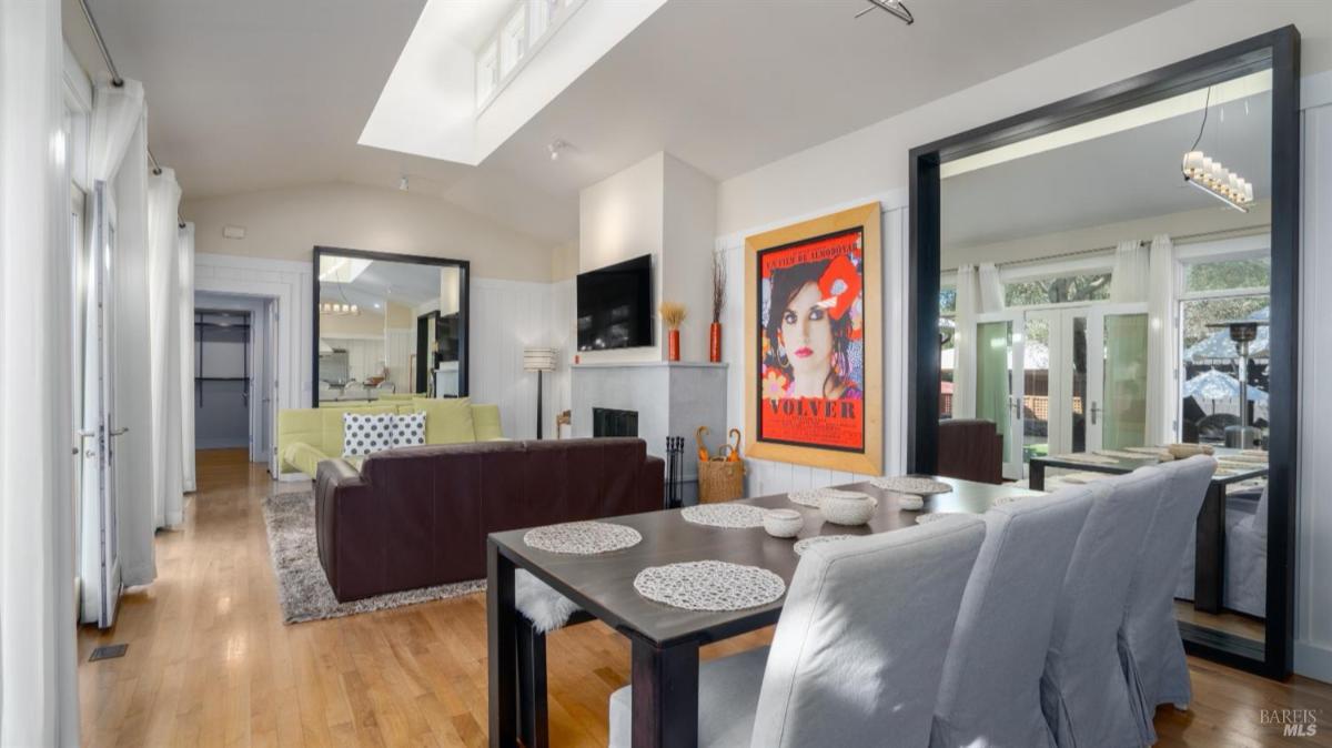Dining area and living room with mirrored walls and large windows.