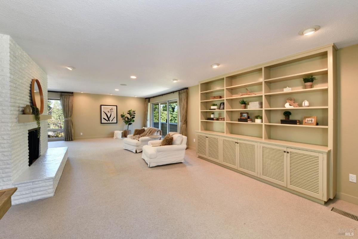 A living room with built-in shelves, a fireplace, and sliding glass doors.
