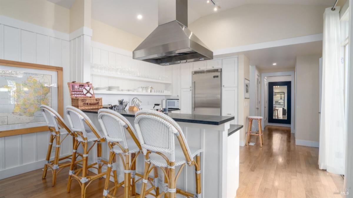 Kitchen with a bar counter, stools, and stainless steel appliances.