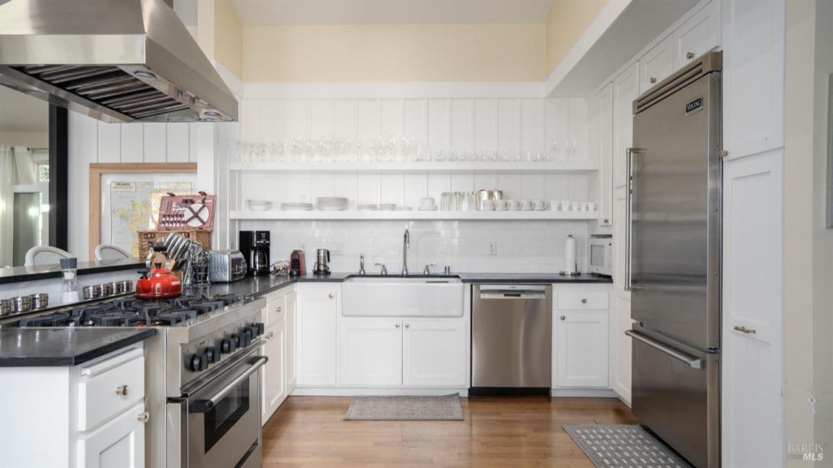 White kitchen featuring a farmhouse sink and stainless steel refrigerator.