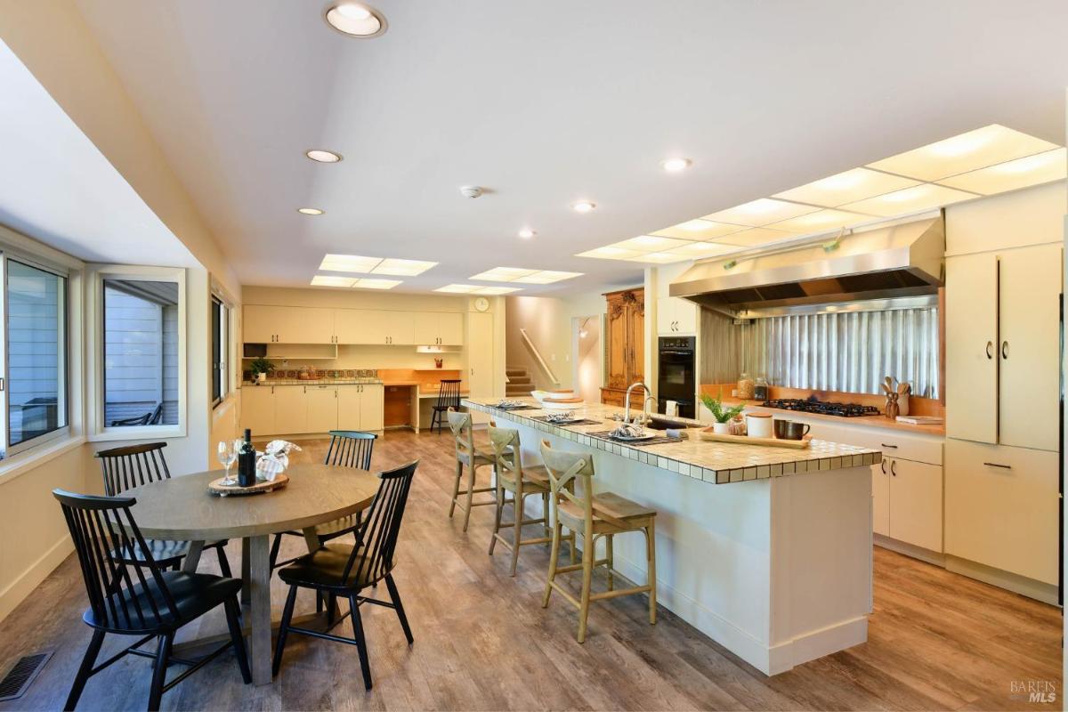 A kitchen with an island, multiple seating areas, and wood flooring.
