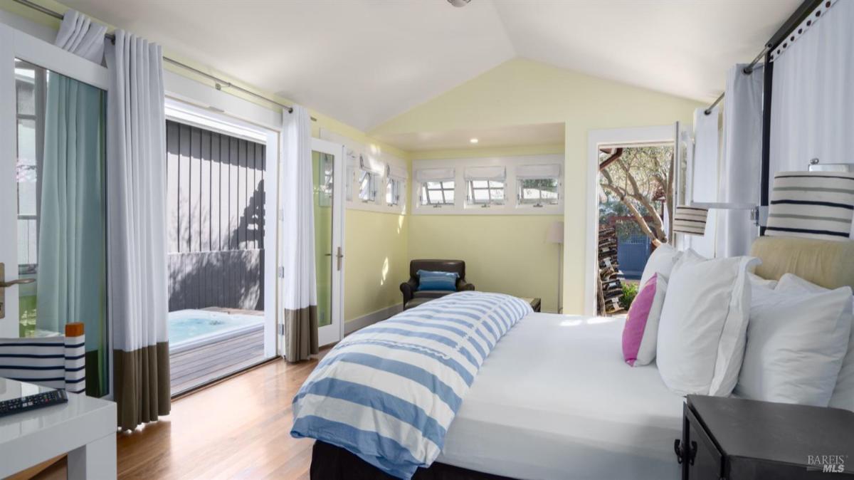 Bedroom with large windows, striped bedding, and access to outdoor space.