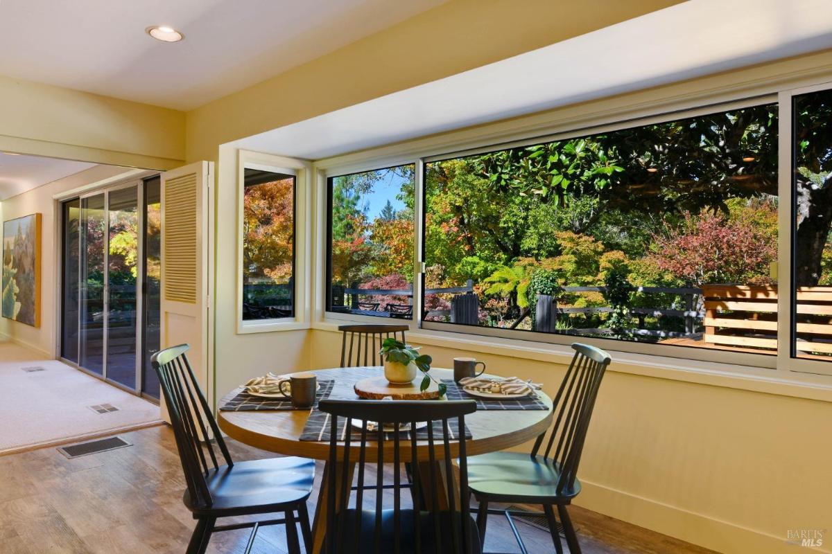 A breakfast nook with a round table and chairs by a large window.