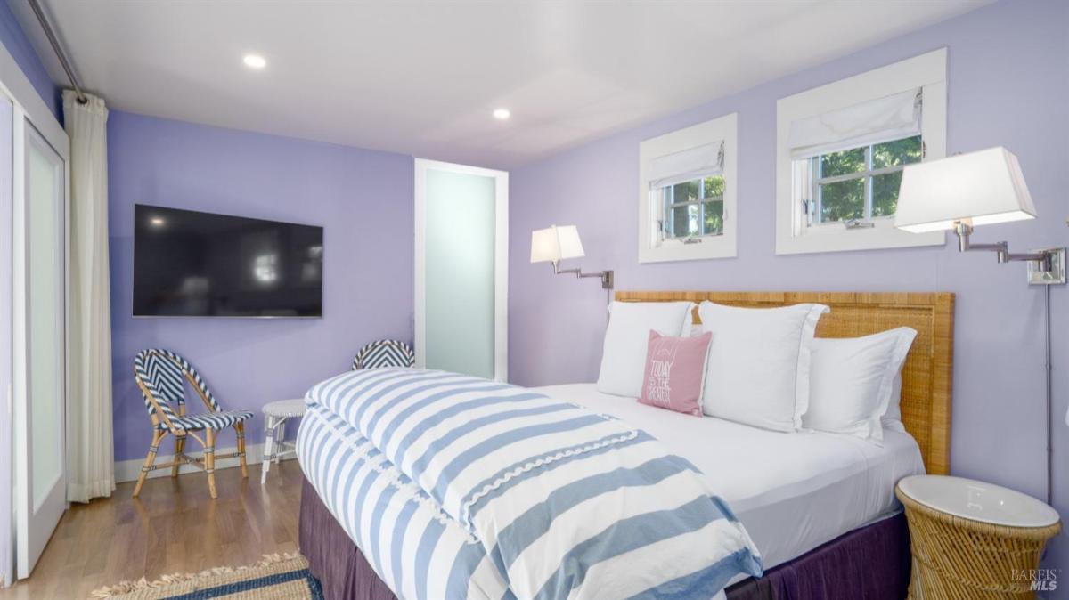 Bedroom with a wall-mounted TV, chairs, and large windows.