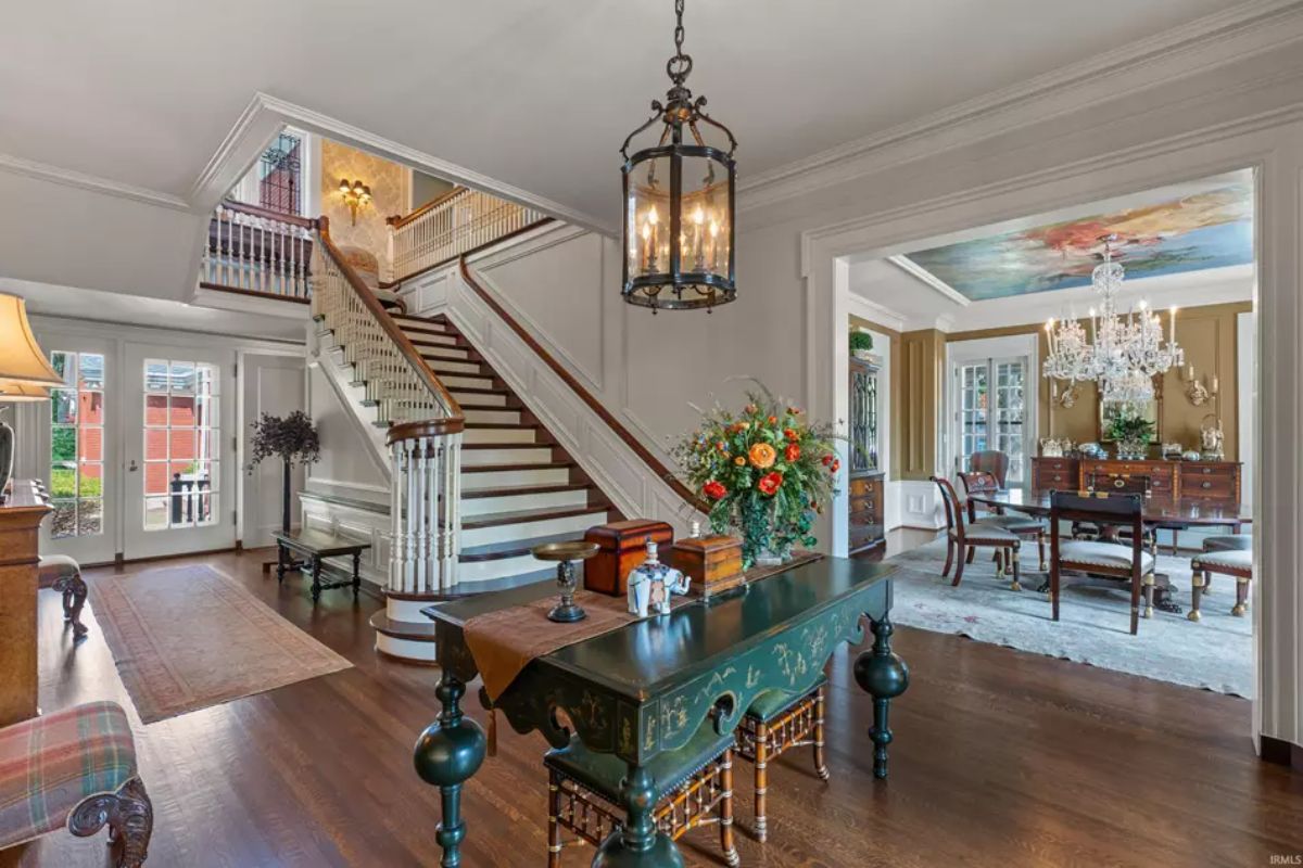 Foyer with a sweeping staircase featuring wooden handrails and white balusters, leading to the upper level.