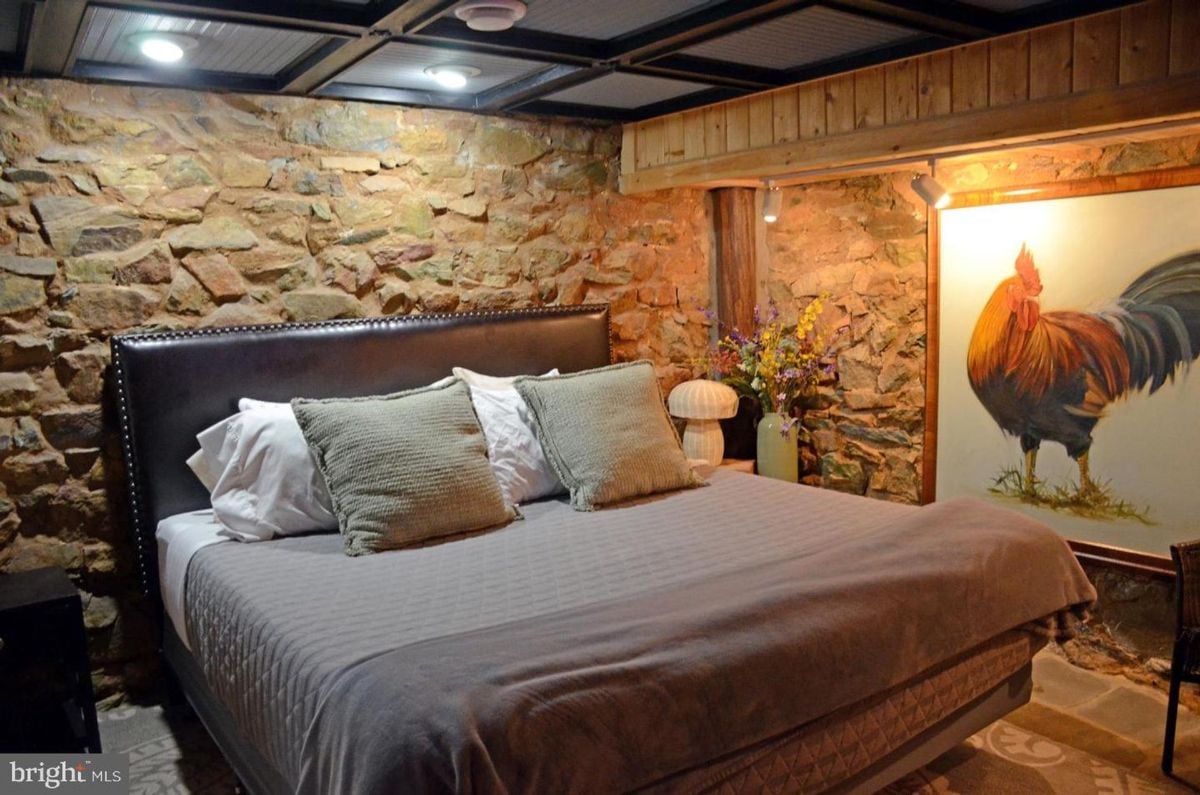Bedroom with a rustic vibe and a unique rooster mural on the stone wall.