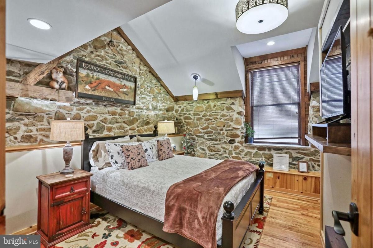 Stone walls and farmhouse decor bring warmth to the inviting bedroom.