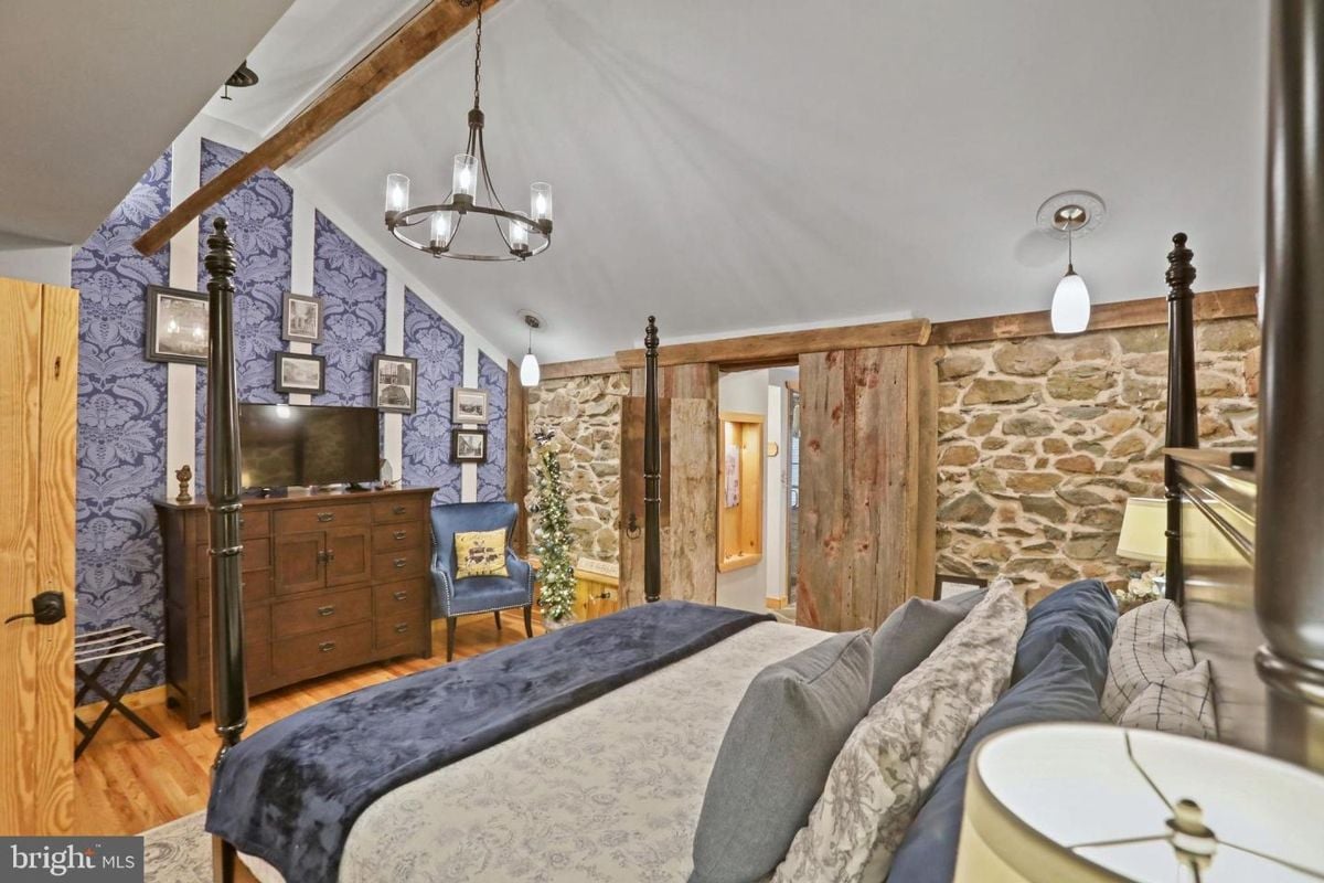 Vibrant blue accent wall and rustic sliding barn doors enhance the stylish bedroom.