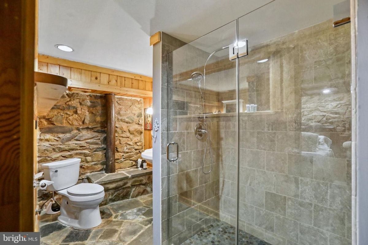 Shower with stone tiles and modern glass enclosure in the bathroom.