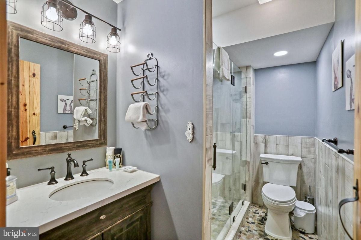 Compact bathroom showcasing a unique wooden vanity and modern glass shower.