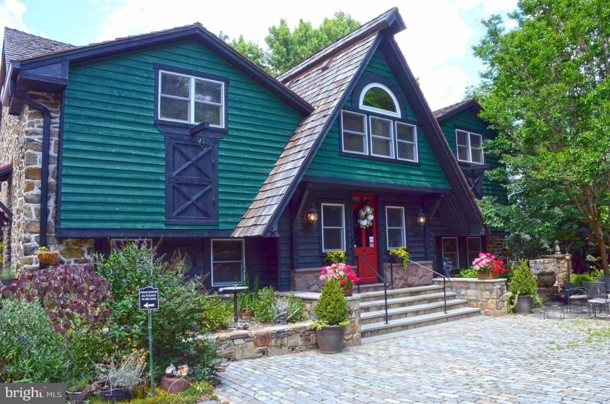 Welcoming front entrance featuring rustic details, vibrant landscaping, and classic barn-style architecture.