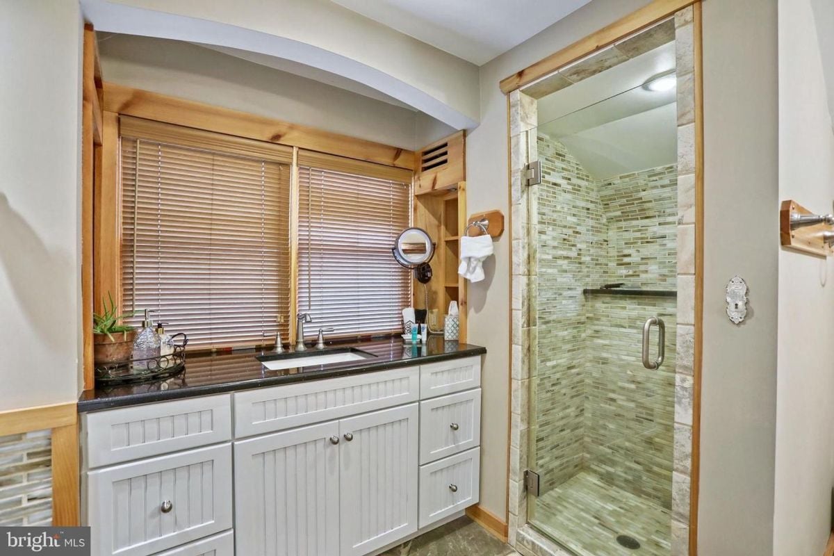 Stone-tiled shower and sleek white vanity complement the bathroom’s natural style.