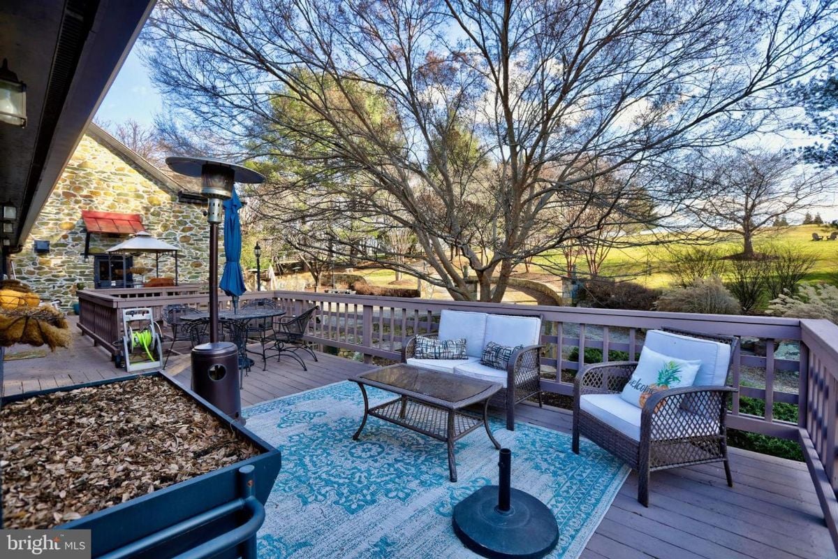 Spacious outdoor deck furnished with wicker seating and a dining area overlooking scenic views.