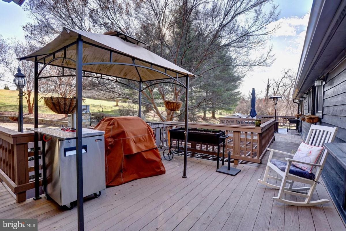 Covered grilling station on a wooden deck surrounded by nature and open air.