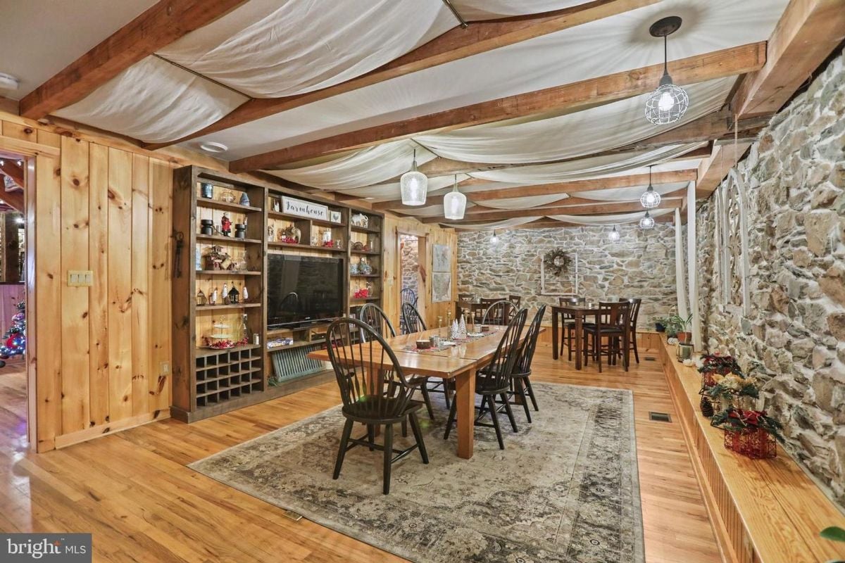 Elegant dining room showcasing a long wooden table, stone walls, and farmhouse-style lighting fixtures.