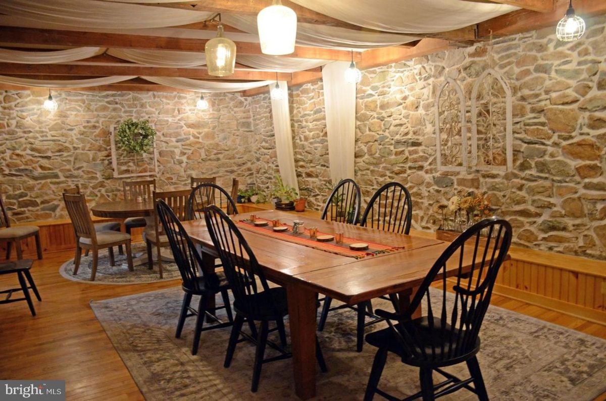 Stone-wall dining room adorned with rustic lighting and elegant wooden furniture.