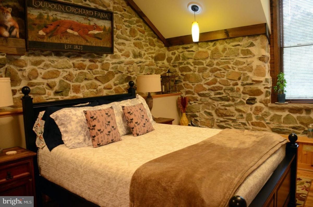 Bedroom framed by exposed stone walls and warm wooden accents.