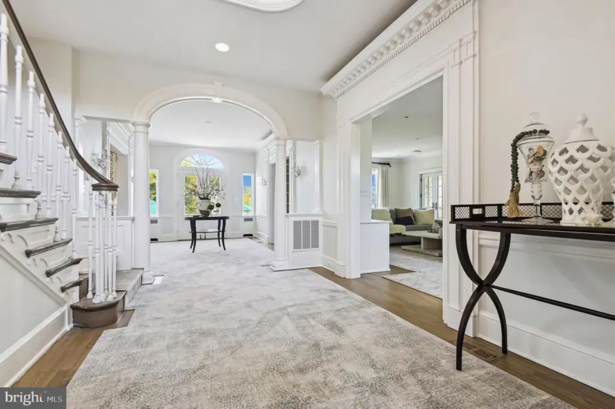 Entryway with arched doorways and intricate white molding.