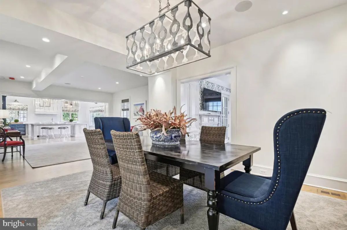 Dining room with a black wooden table surrounded by a combination of woven and upholstered chairs.