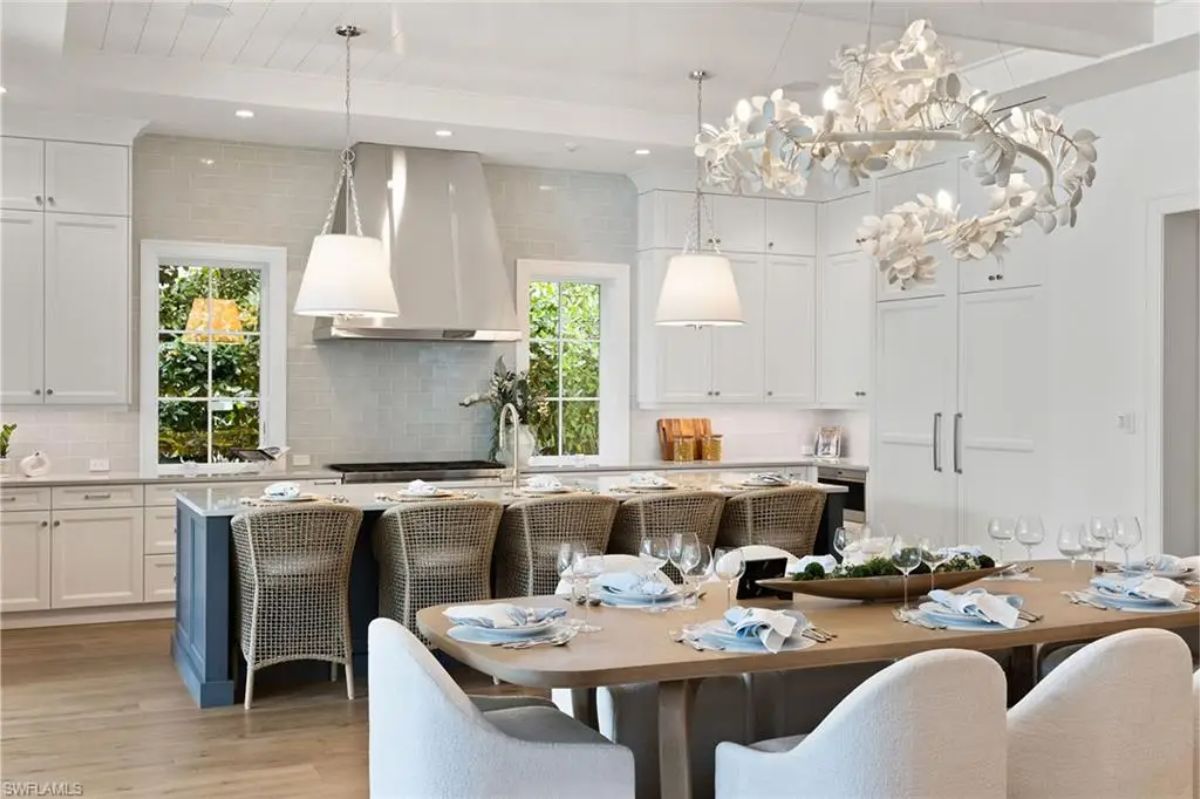 Dining setup with a view of the modern kitchen and a statement chandelier above the table. 