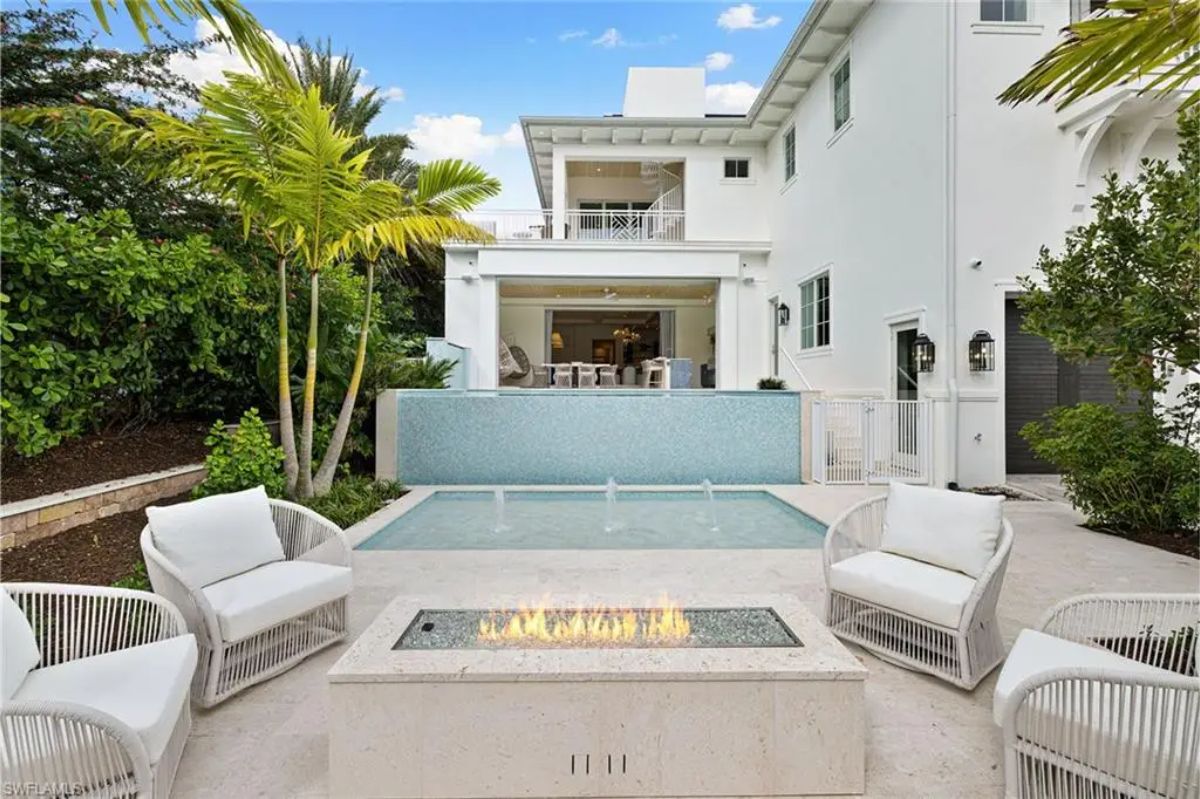 Daytime view of the backyard seating area with a fire pit, small pool, and greenery. 