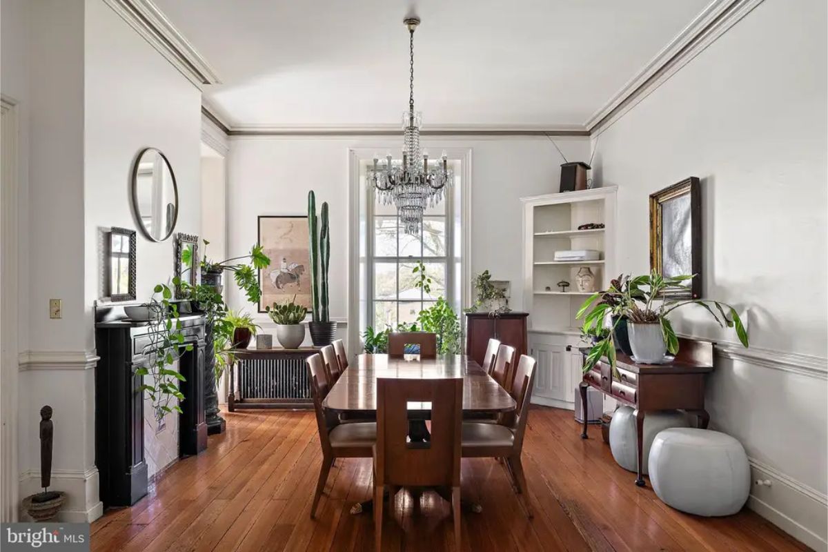 Bright dining space with a large wooden table and matching chairs on polished hardwood floors.