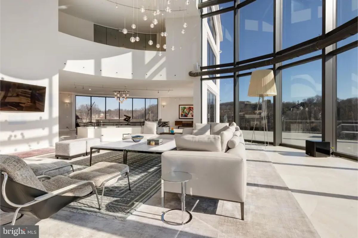 Spacious, well-lit living space with contemporary furniture and floor-to-ceiling glass windows. 