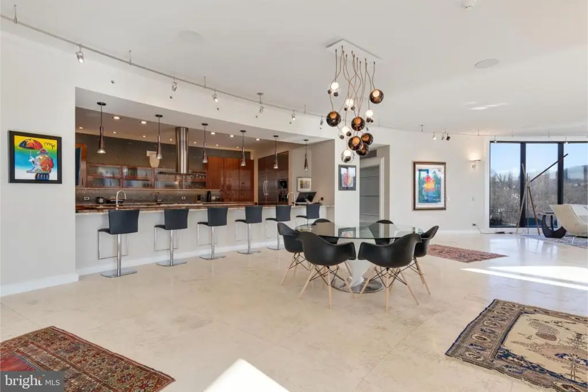 Kitchen showcases an expansive island, stainless steel appliances, and wood cabinetry with sleek finishes. 