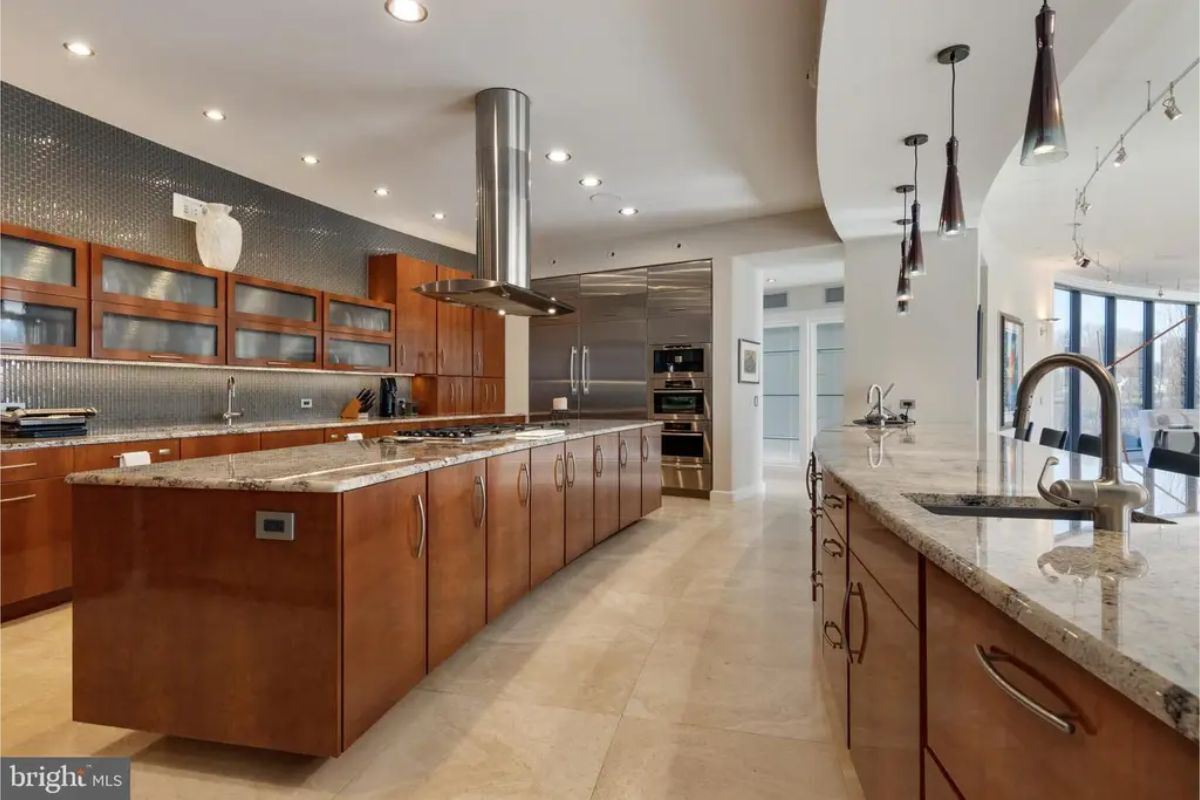 Kitchen layout includes dual sinks, ample countertop space, and pendant lighting for a modern aesthetic. 