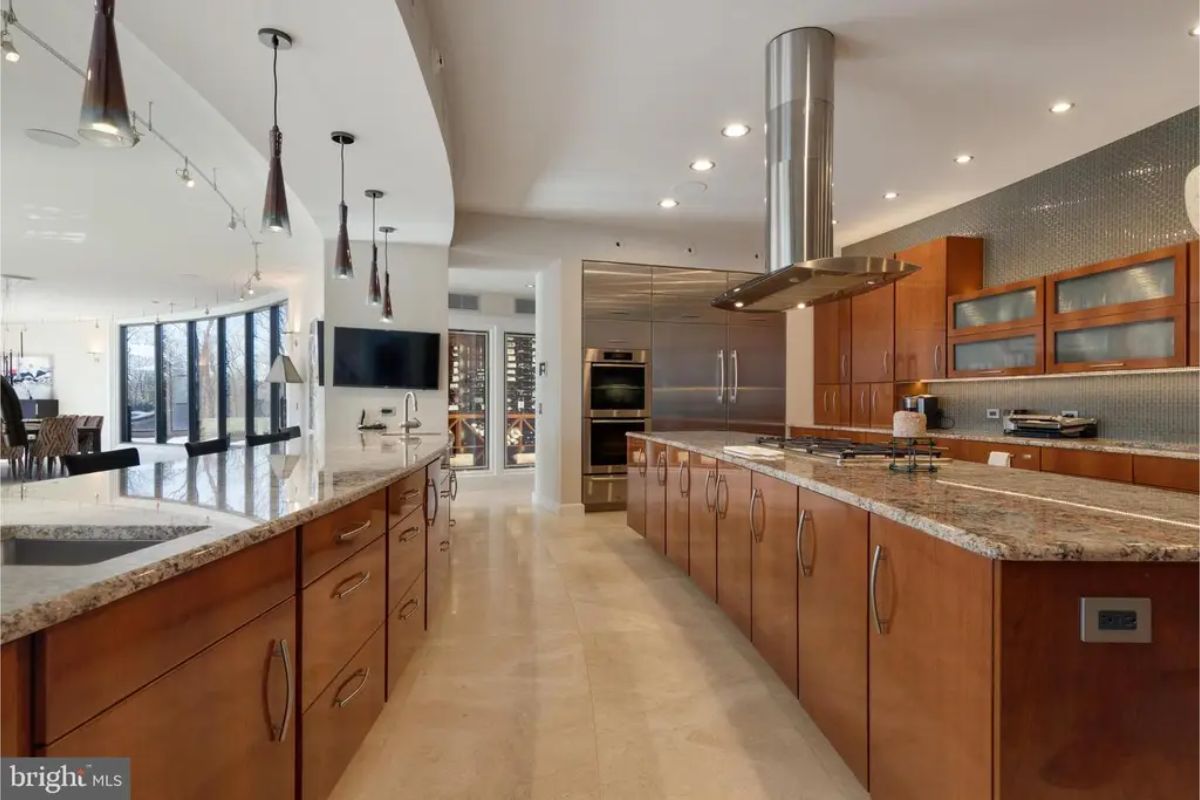 Kitchen layout includes dual sinks, ample countertop space, and pendant lighting for a modern aesthetic. 