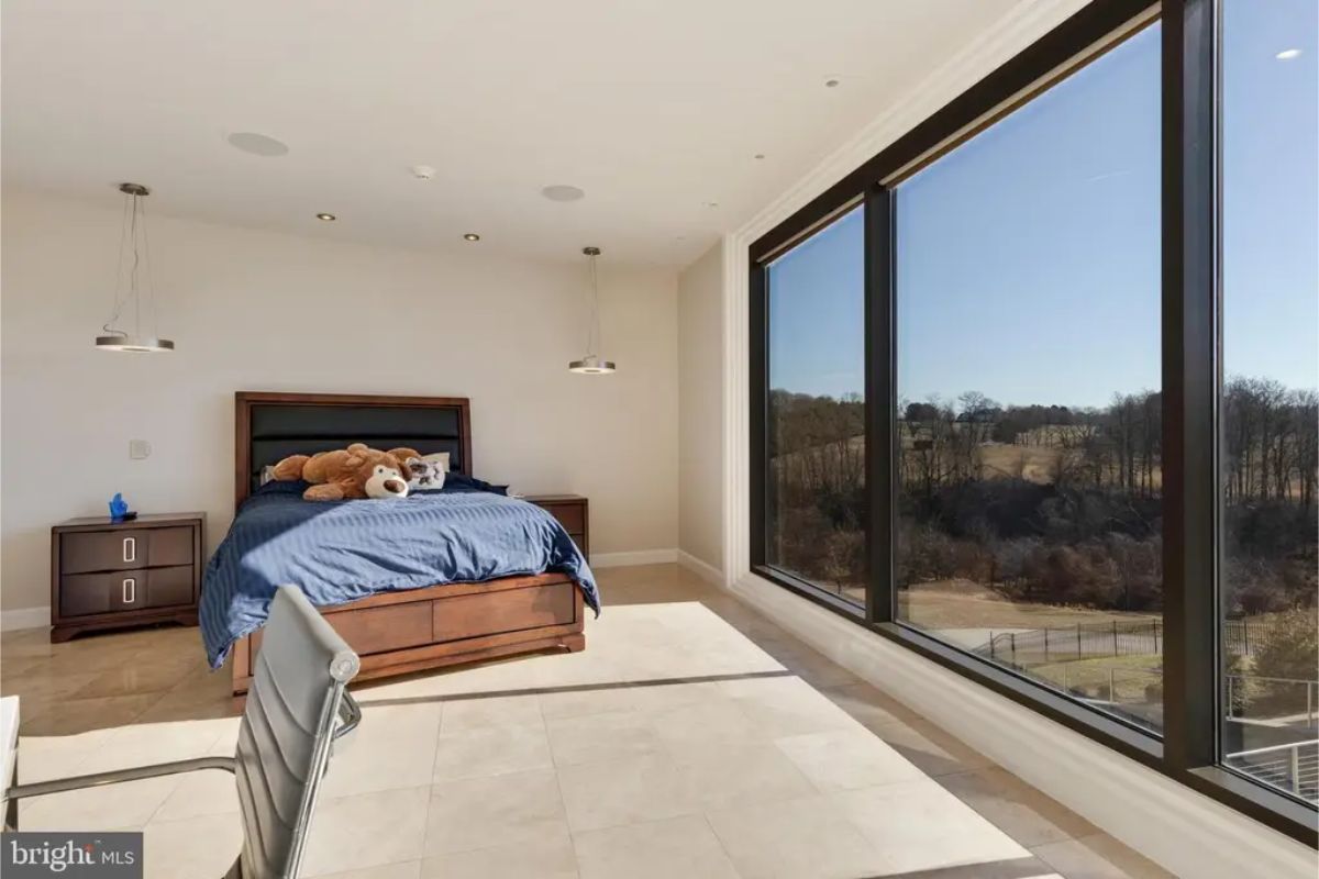 Bedroom includes a plush bed with large glass windows showcasing nature views. 