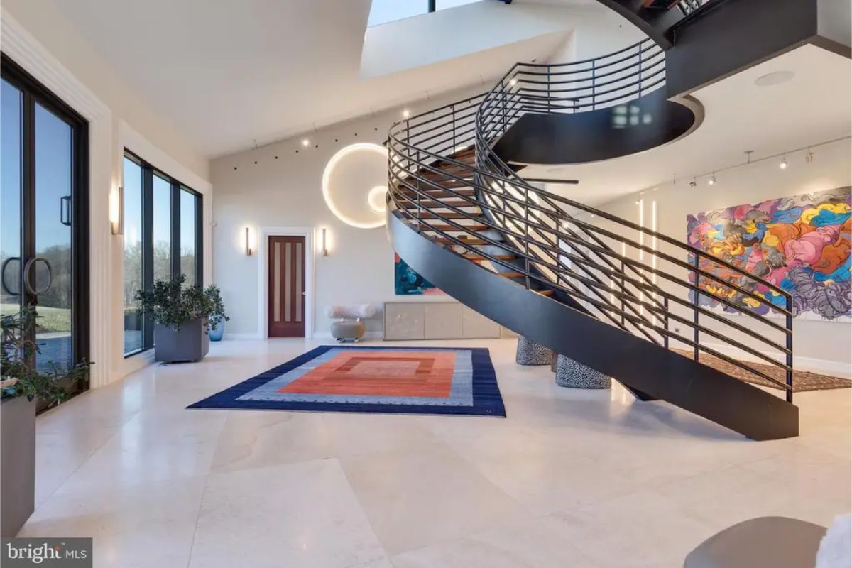 Entryway highlights a grand spiral staircase with a contemporary design and colorful art pieces. 