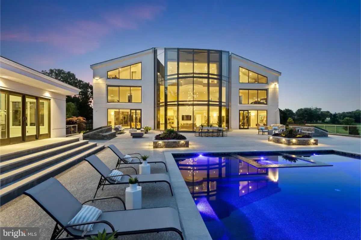 Close-up view of the home's glass facade showcasing poolside area with elegant seating. 